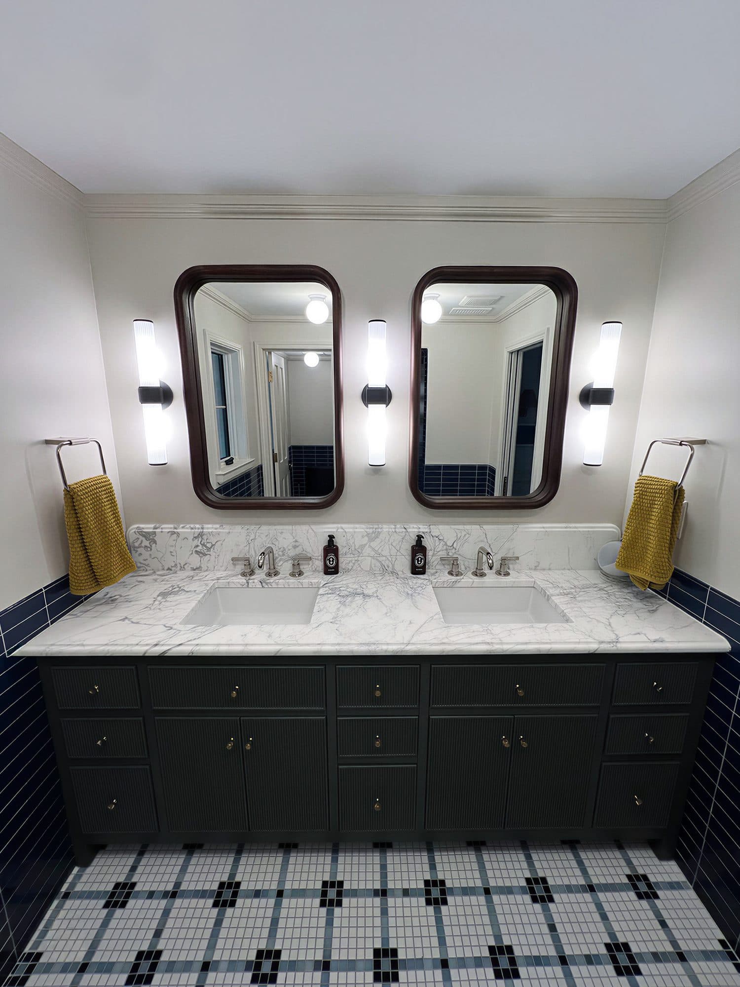 Navy blue double-vanity bathroom renovation with marble countertop and arched wood-framed mirrors