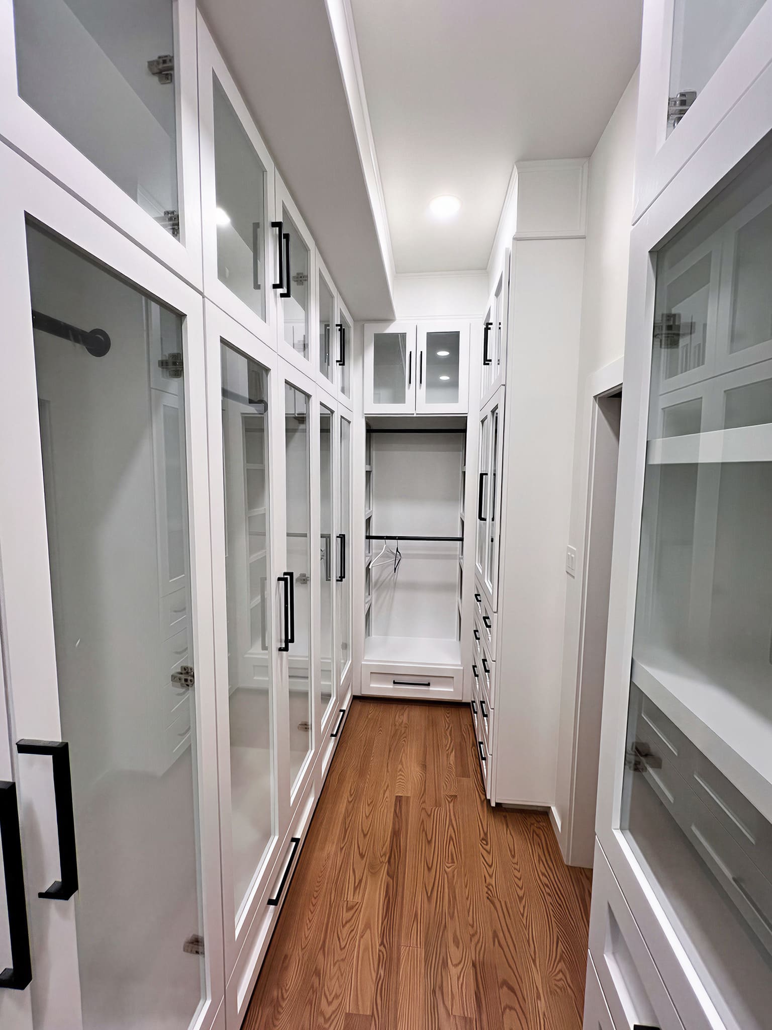 Custom walk-in closet with glass-front white cabinetry