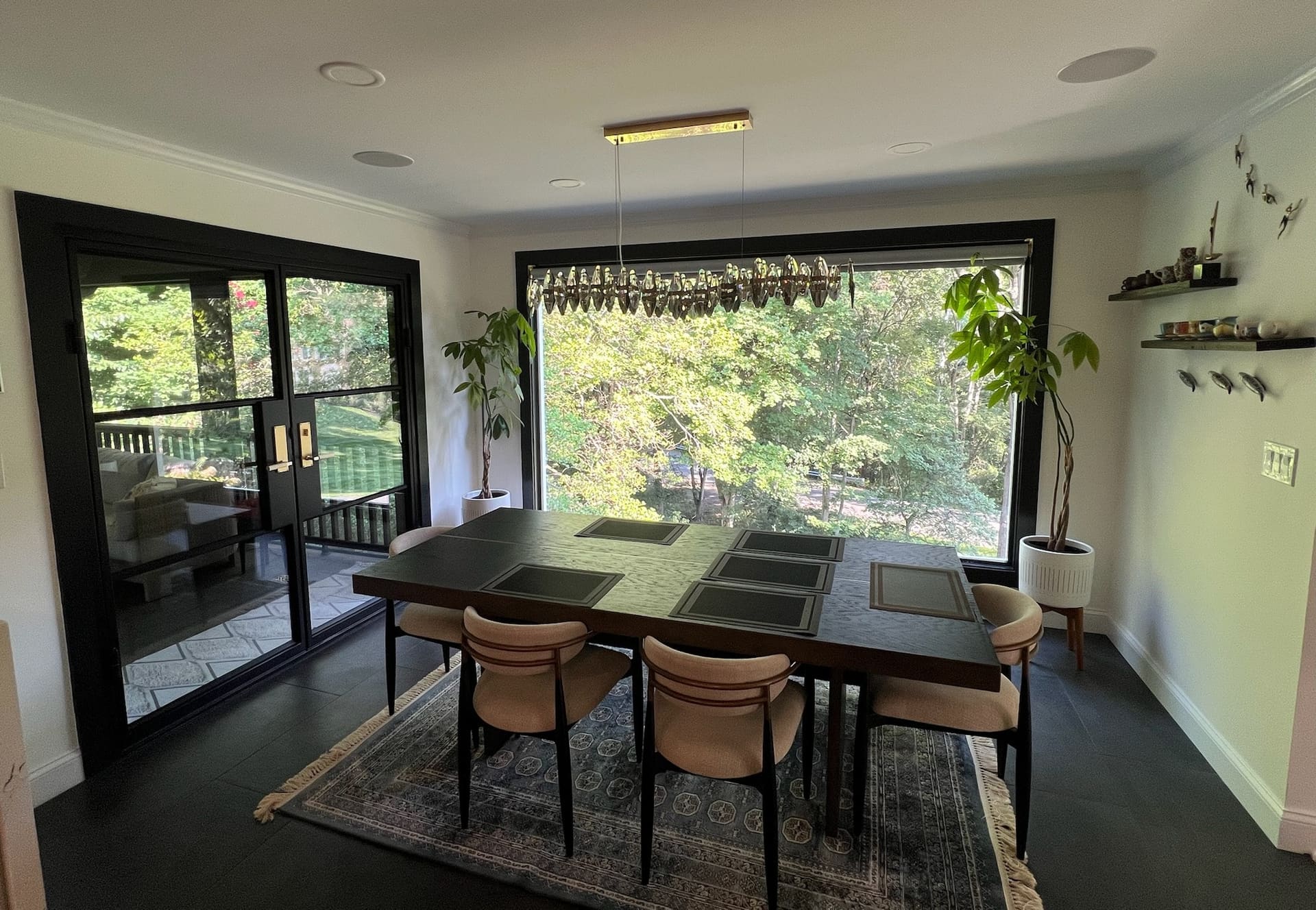 Dining room with black-framed windows and forest view