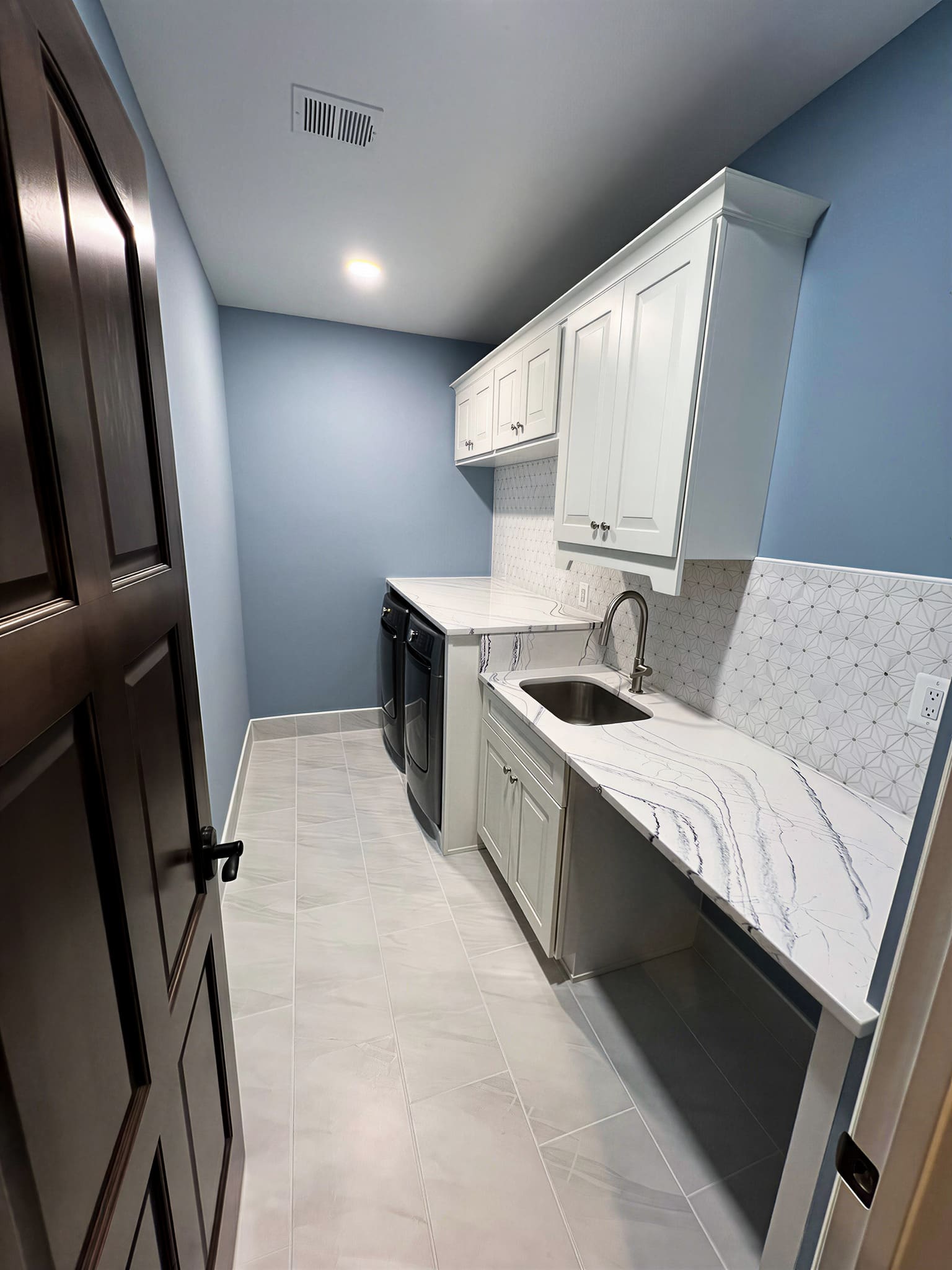Laundry room with mosaic tile backsplash and marble countertop