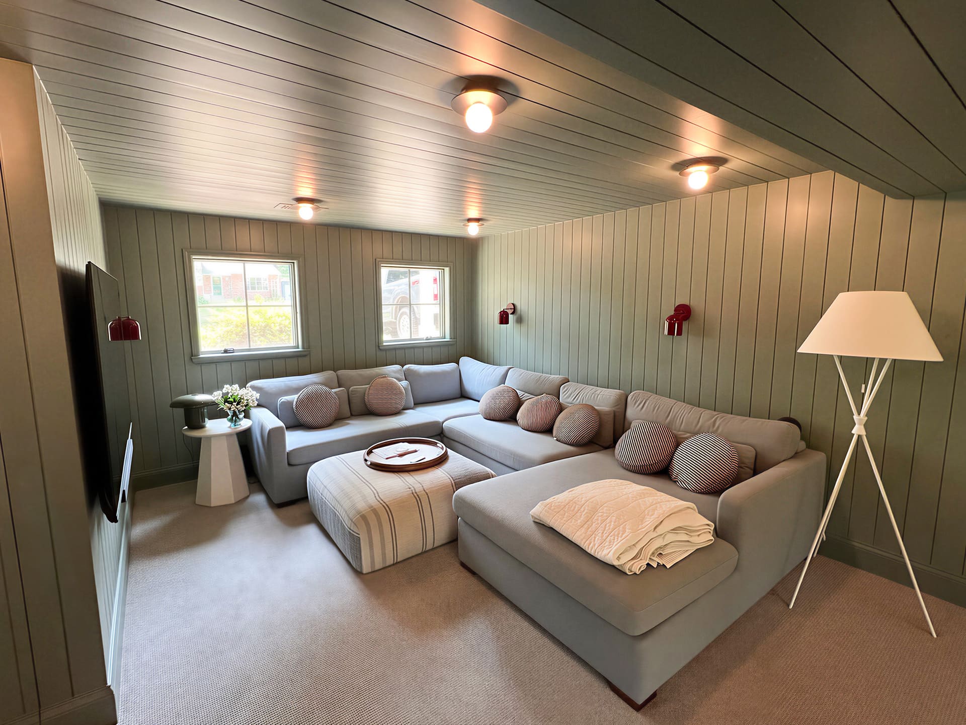 Basement media room with green shiplap paneling and sectional sofa