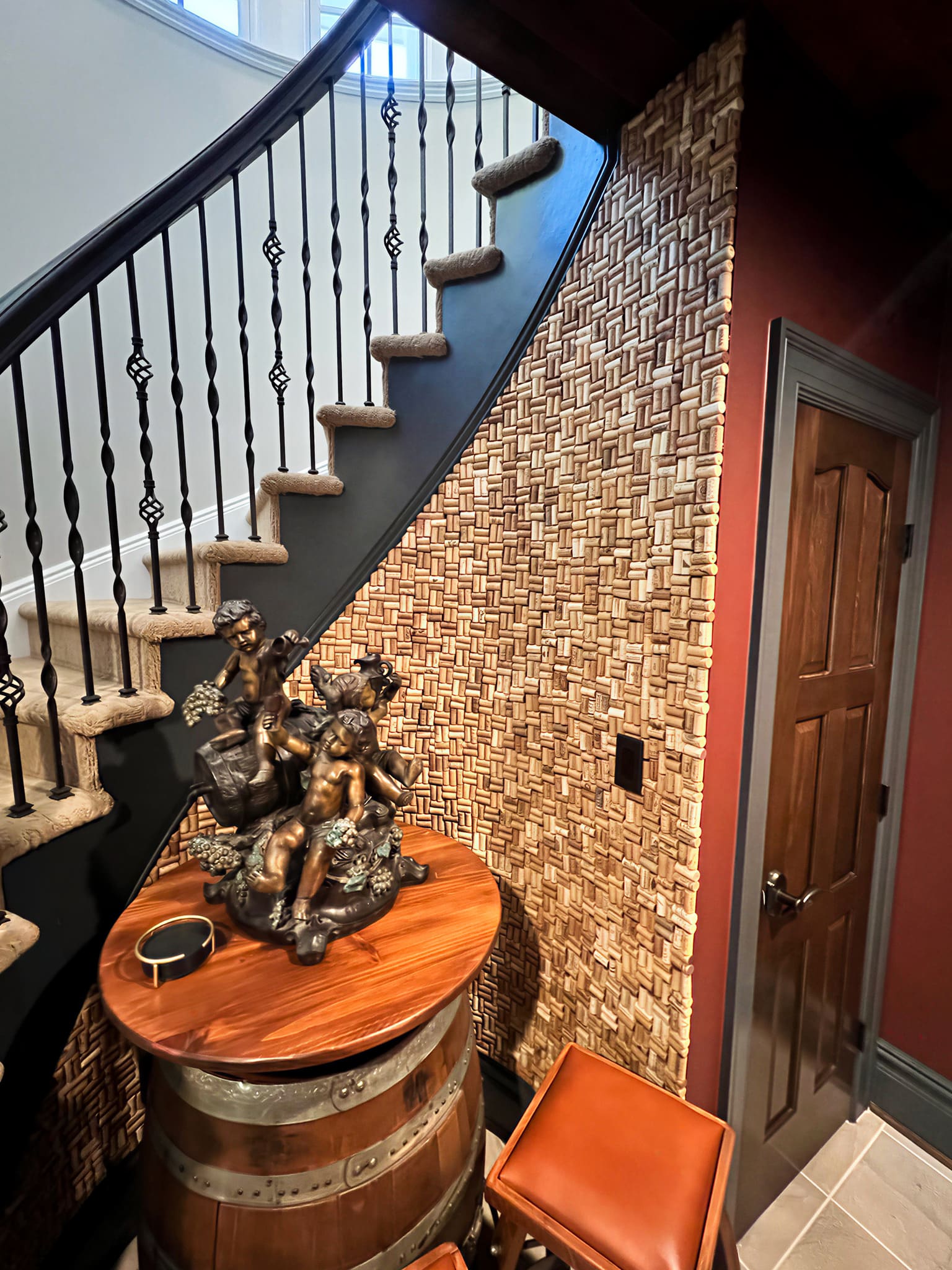 Custom wine cork accent wall beneath a curved staircase