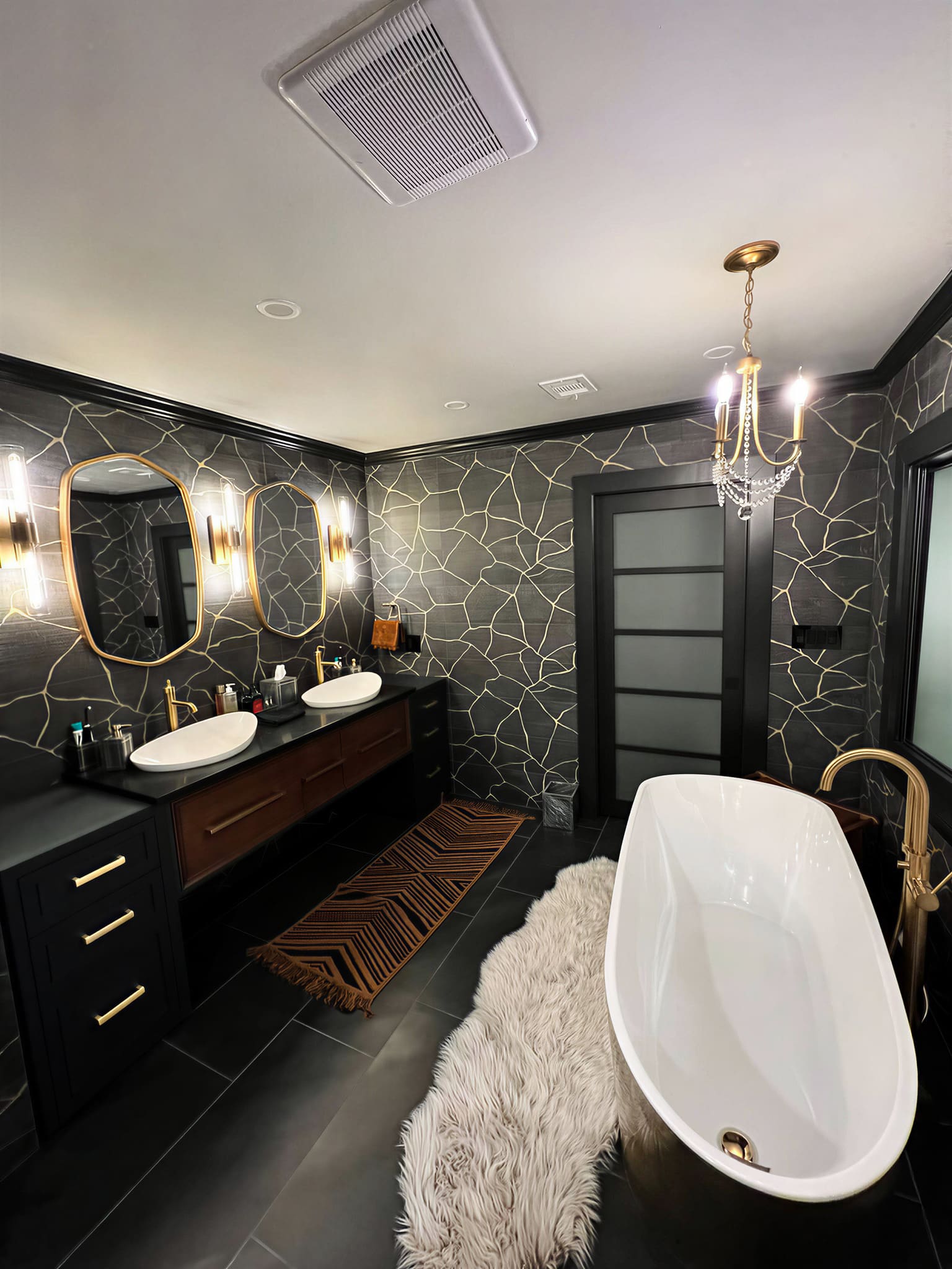 Black and gold primary bathroom with crackle wallpaper and chandelier