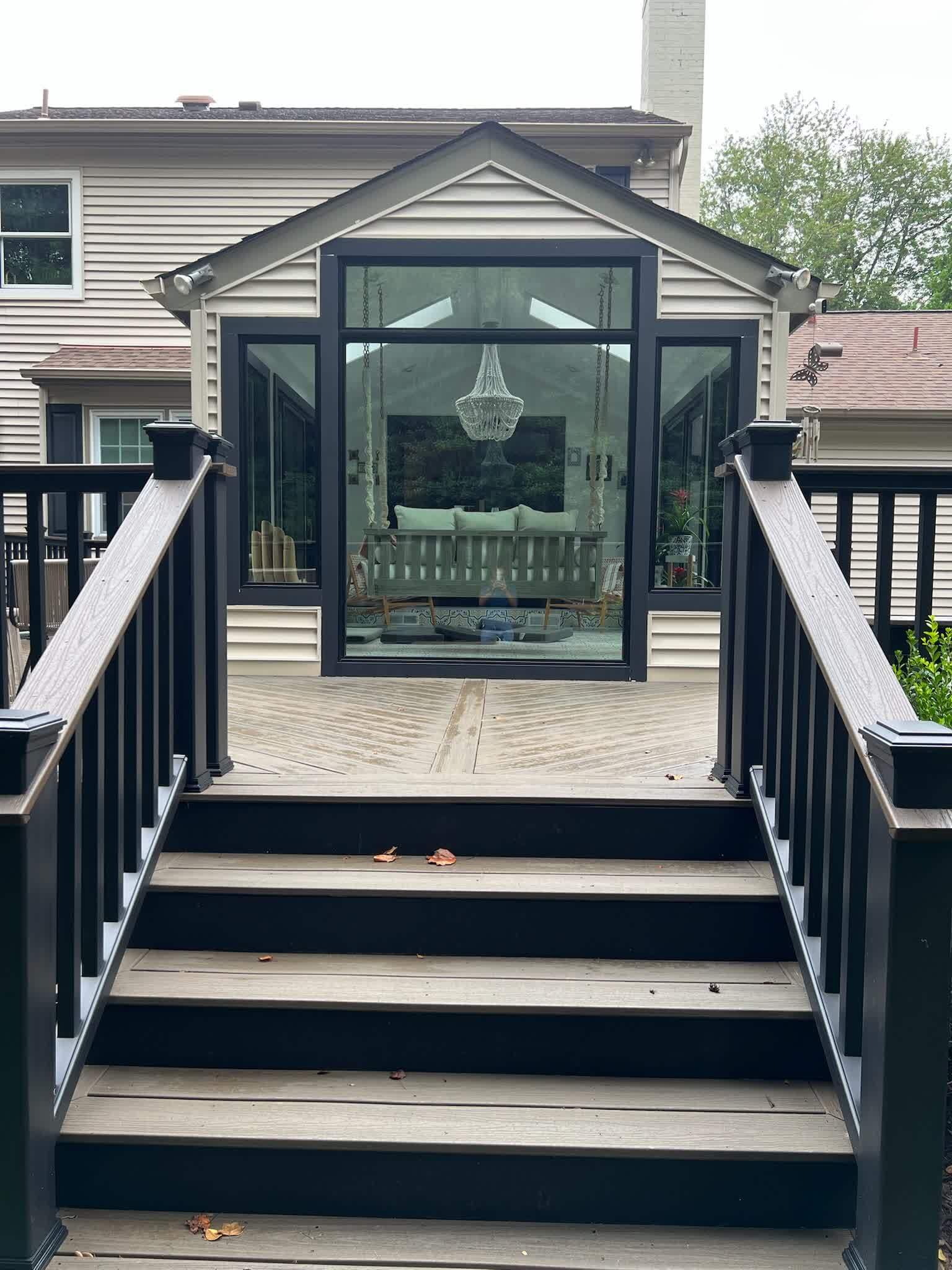 Glass sunroom addition viewed from the deck stairs, chandelier visible inside