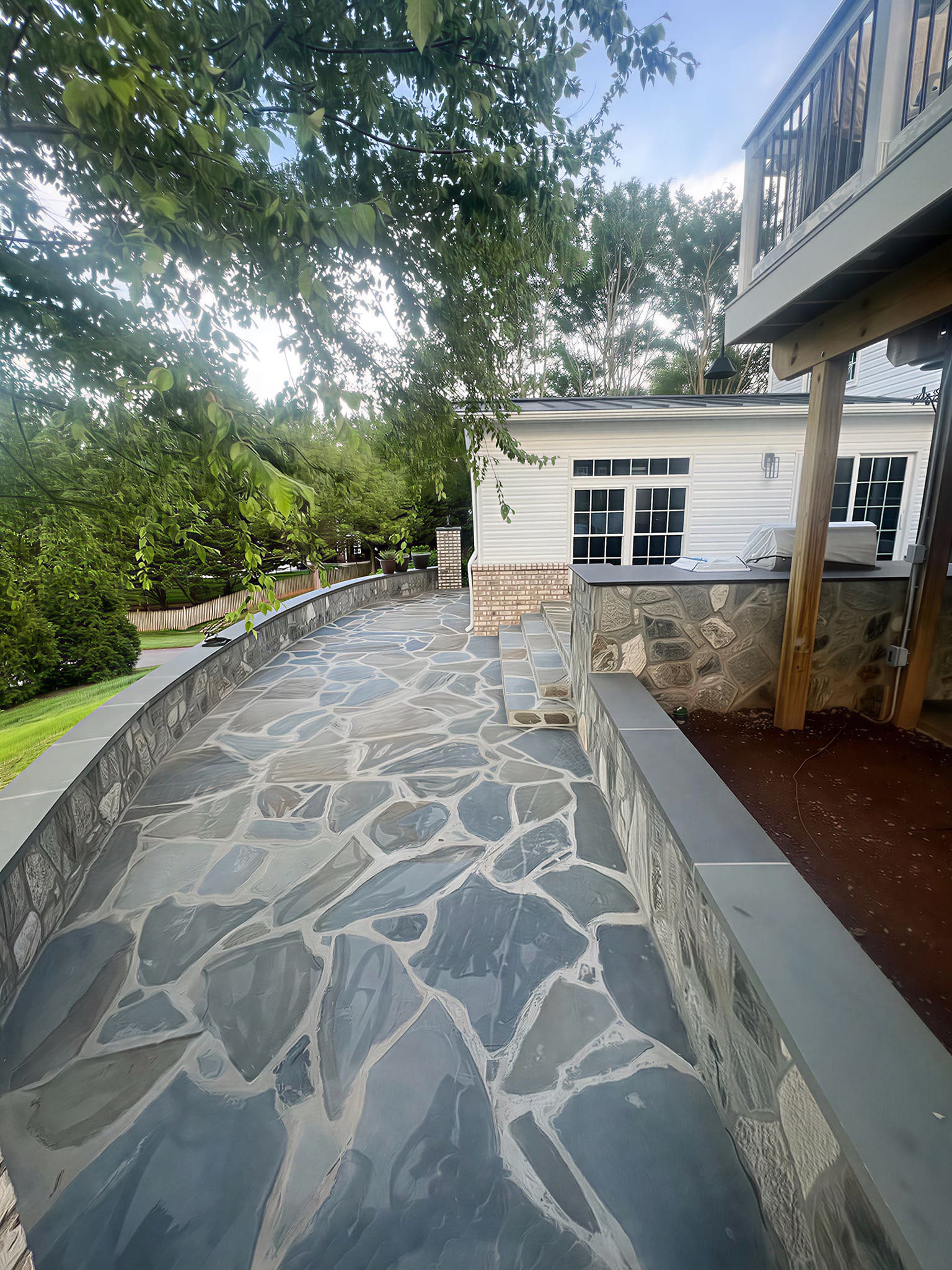 Curved flagstone patio walkway with stone-clad outdoor kitchen bar